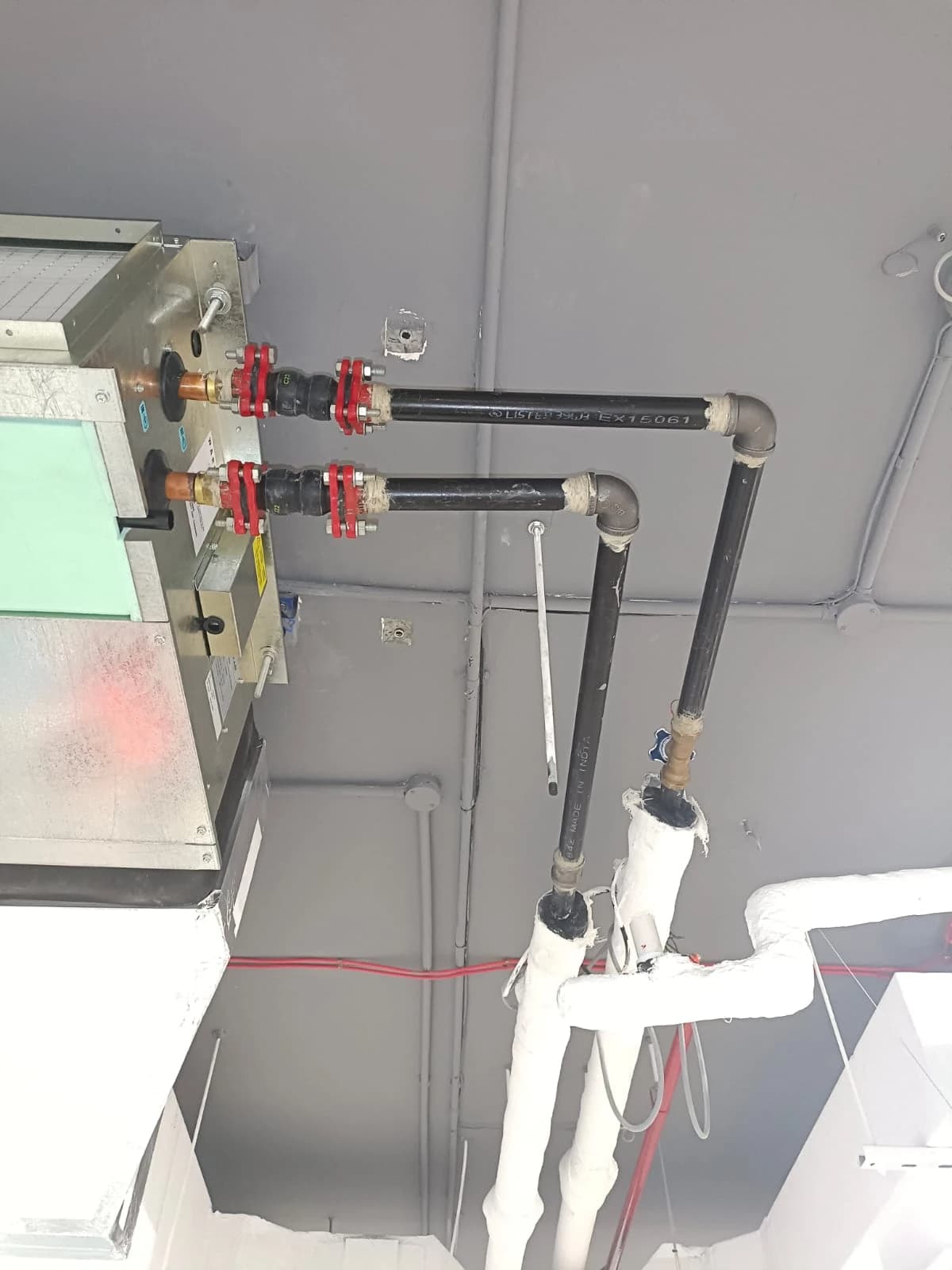 Ceiling-mounted AC unit with insulated pipework and valves