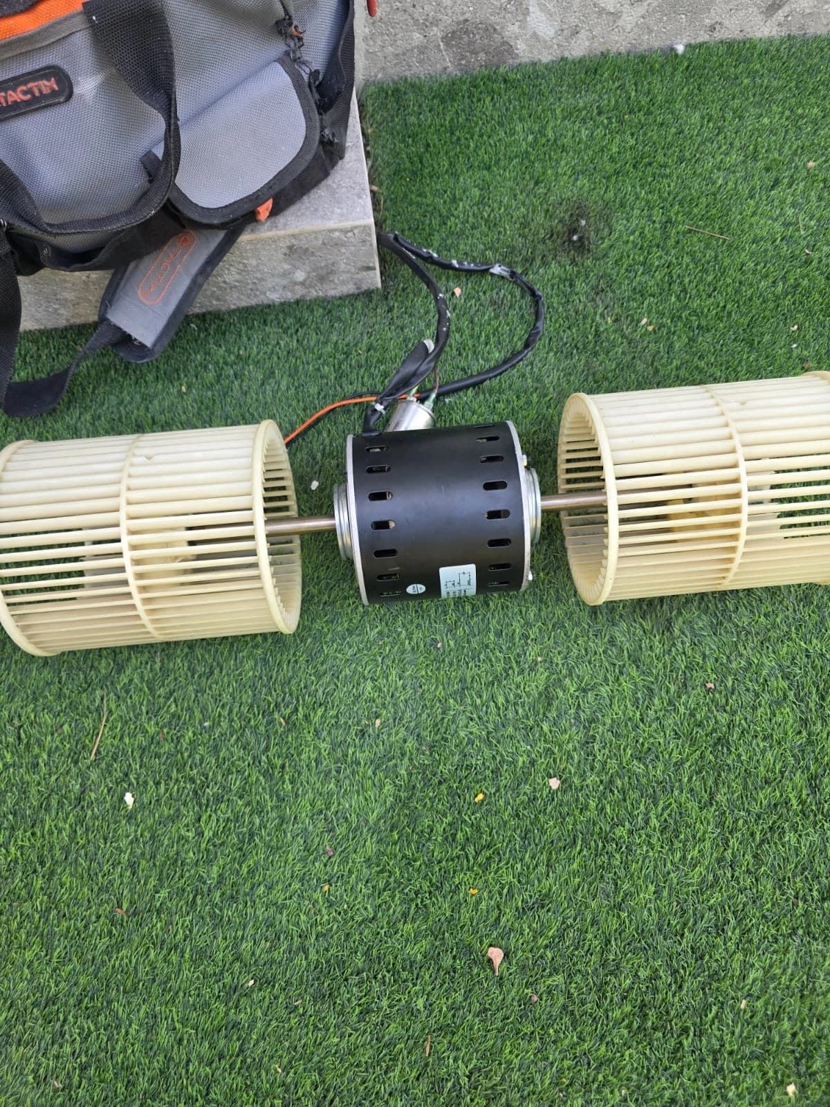 AC blower motor and wheels removed for cleaning, with a vacuum cleaner beside them