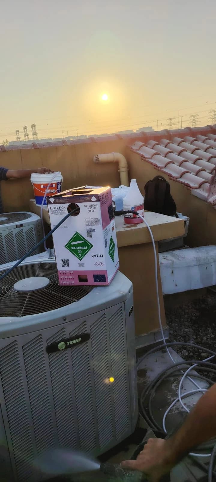 Refrigerant cylinder on top of a rooftop condenser unit at sunset