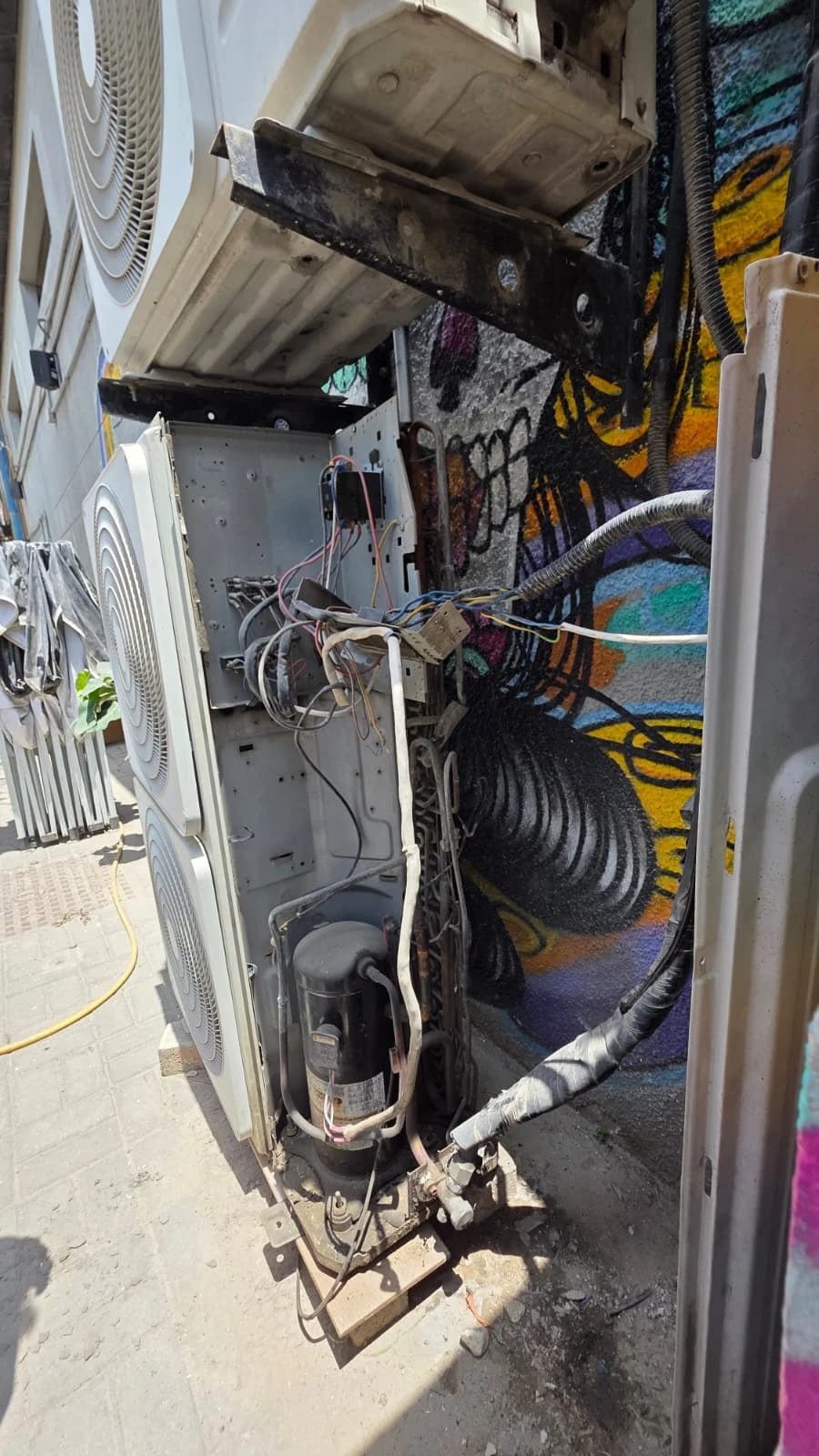 Outdoor AC unit with its side panel removed, showing wiring and compressor