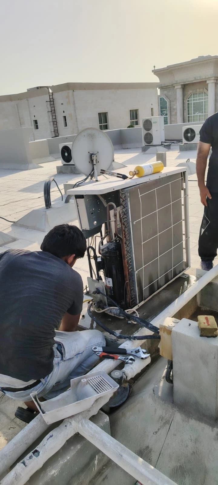 Technicians installing outdoor AC units on a villa rooftop
