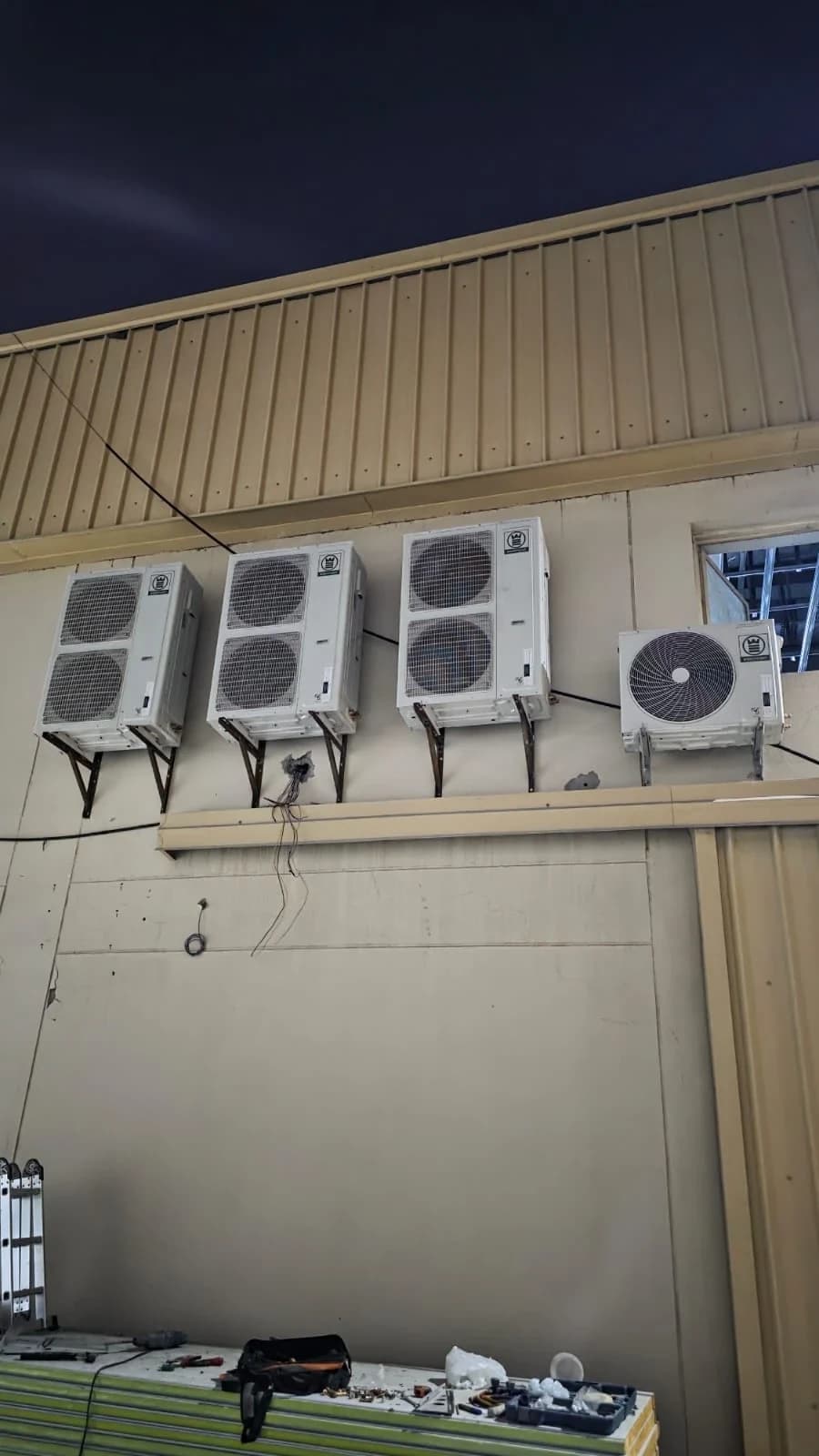 Outdoor AC units mounted on a building wall in the evening