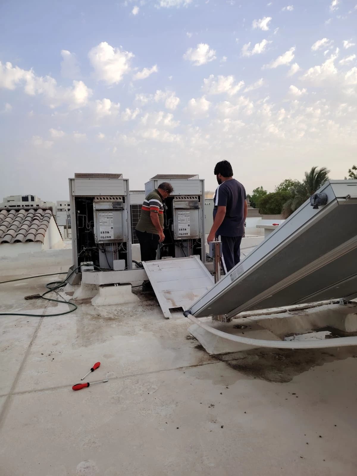 Technician beside open outdoor AC units on a rooftop