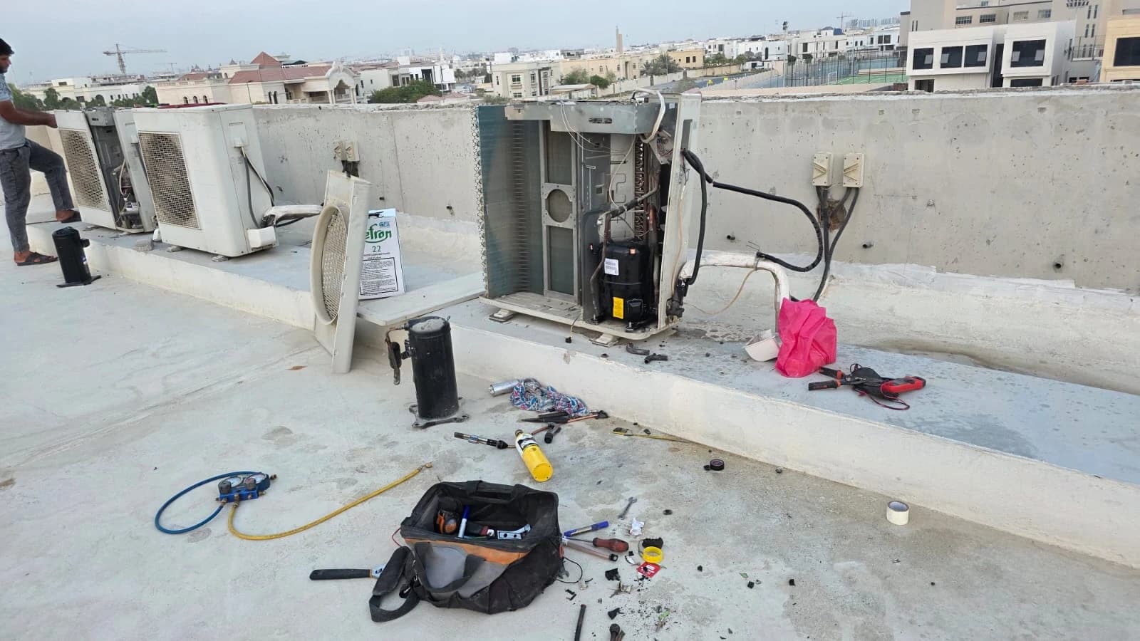 Outdoor AC units opened for repair on a rooftop with tools laid out
