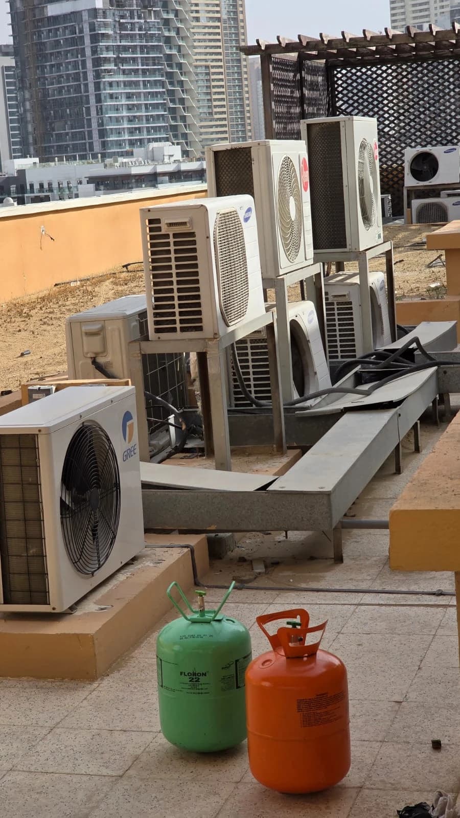 Refrigerant cylinders next to outdoor AC units on a rooftop