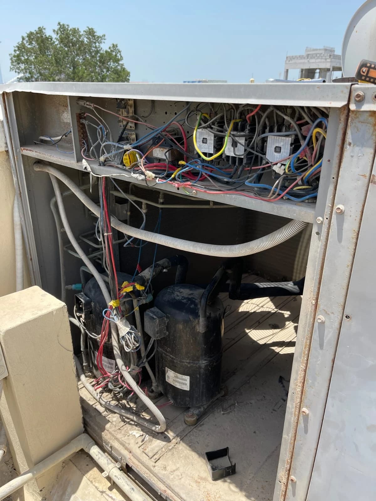 Open outdoor condensing unit showing its wiring and compressor for inspection