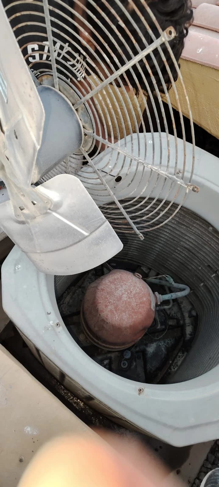 Top view into a condensing unit with the fan guard opened, showing the compressor
